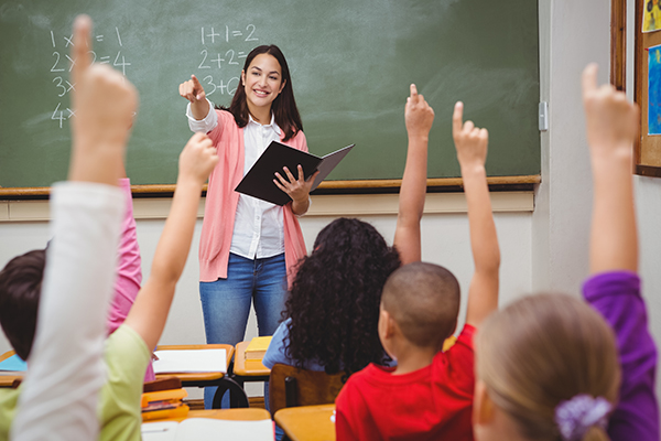 Teacher teaching a class with children's' hands raised