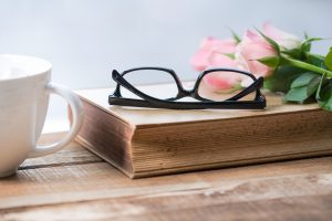 Reading glasses on book with rose