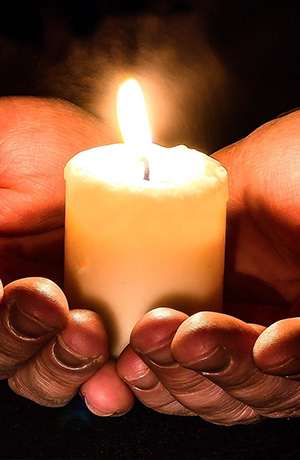 Hands holding lit candle