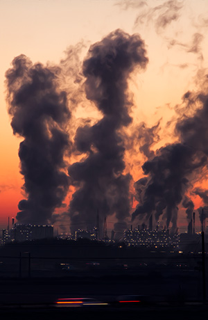 Factory smokestacks against sunset sky