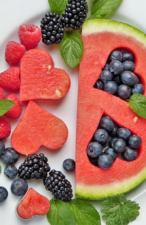 Plate of watermelon and berries, with heart shapes cut out of the melon